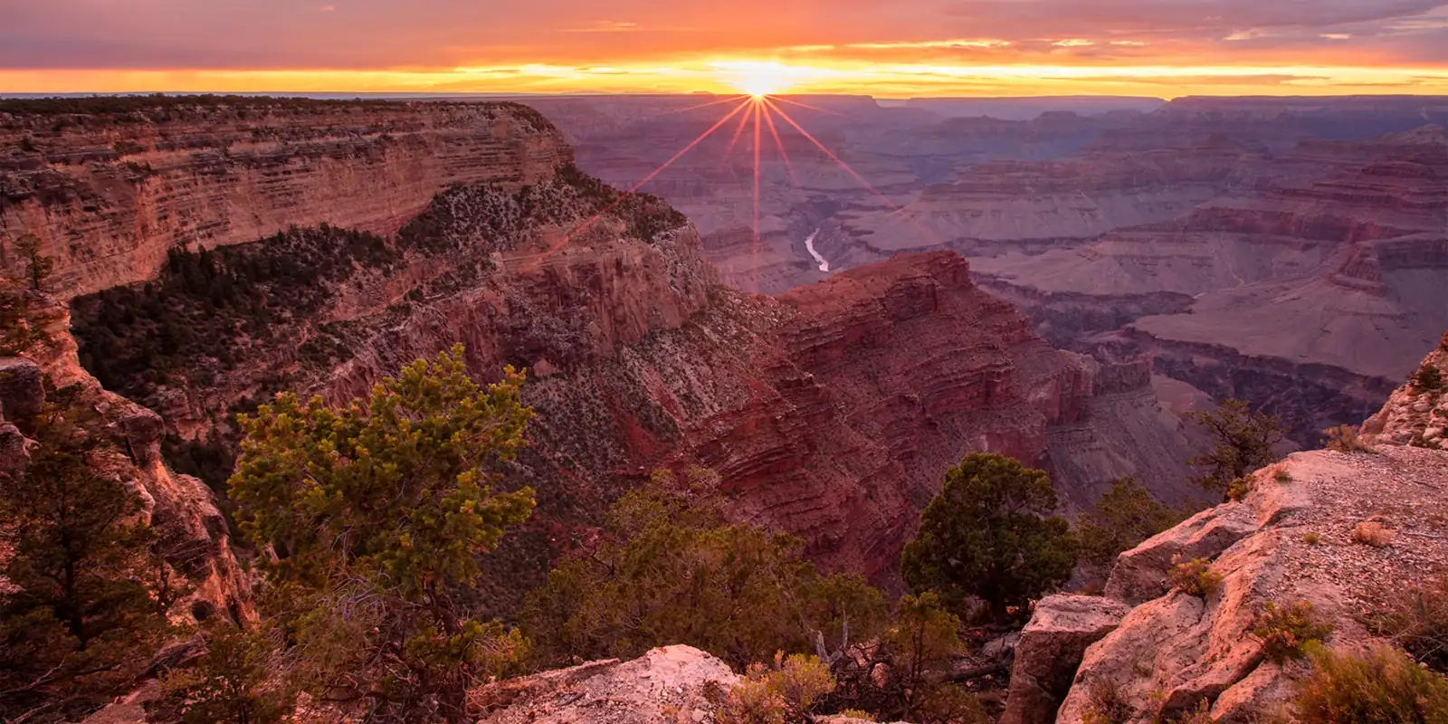 Sunset bursting over the layered cliffs of the Grand Canyon from Hopi Point, the Colorado River glinting below