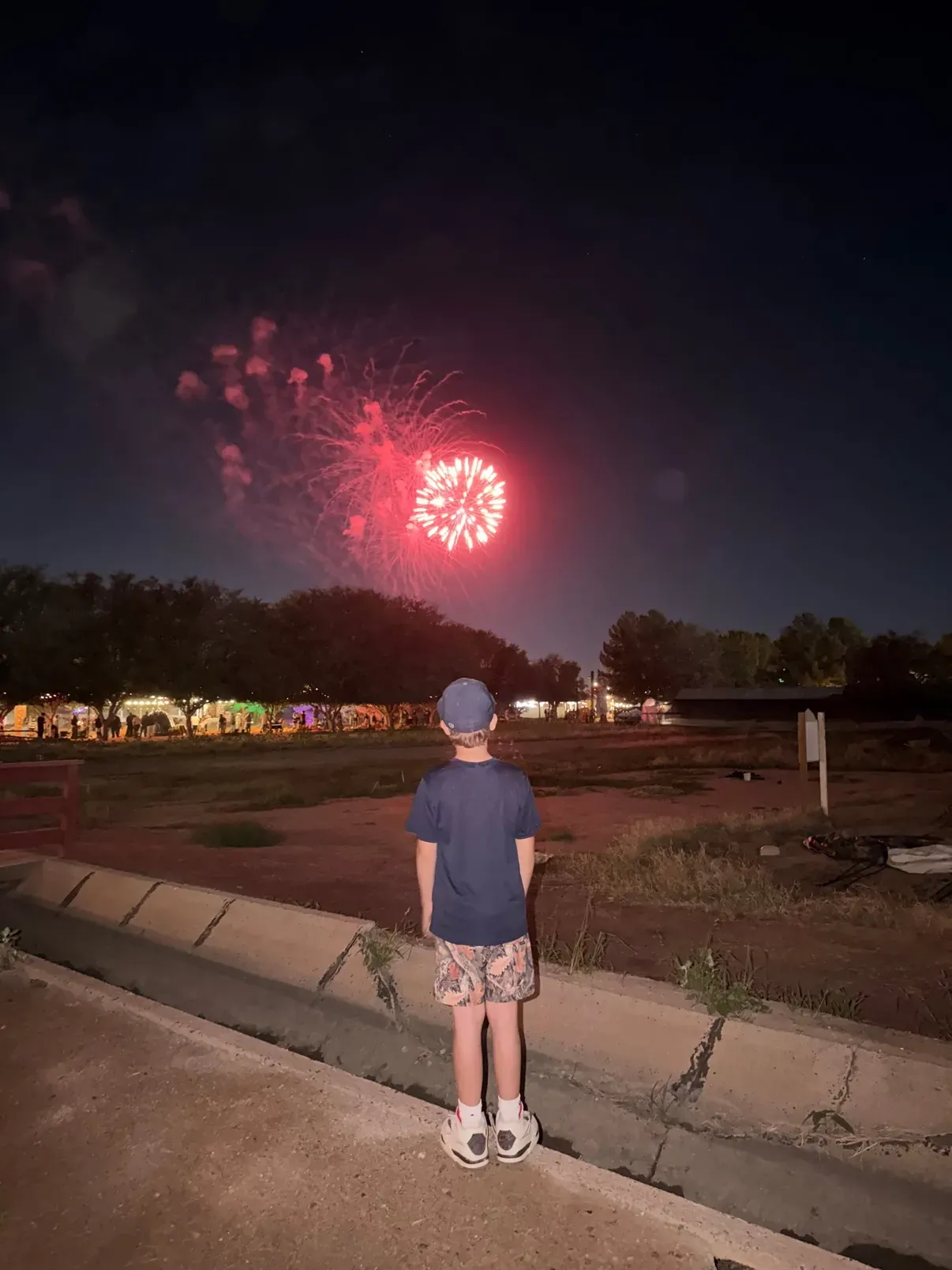 Watching the red fireworks finale from behind, the midway lights glowing in the distance