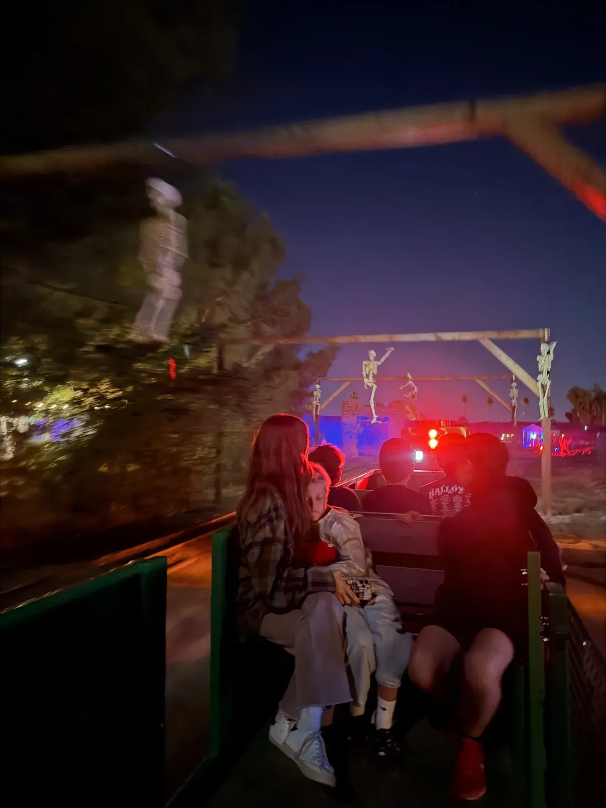 Riding the spooky night train past skeletons mounted on the signal gantry, lit red and blue
