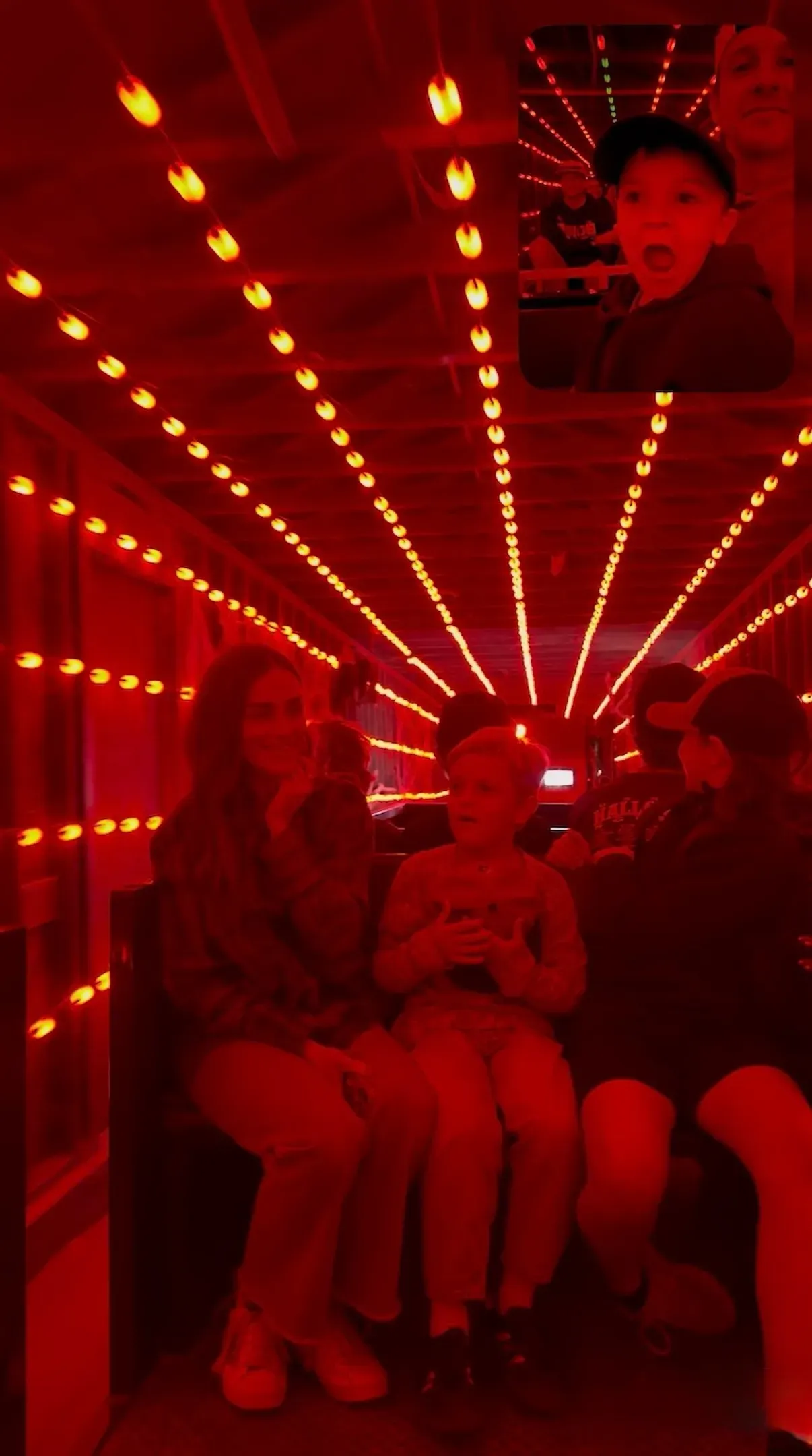 Inside the spooky train car, washed in red light from strings of bulbs overhead